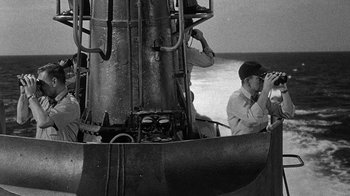 Movie still from “Run Silent Run Deep” (1958), directed by Robert Wise – A man is looking through binoculars while sitting on a boat; Medium shot, High angle