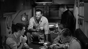 Movie still from “Run Silent Run Deep” (1958), directed by Robert Wise – A group of men sitting around a table eating food; Medium shot, Over the shoulder angle