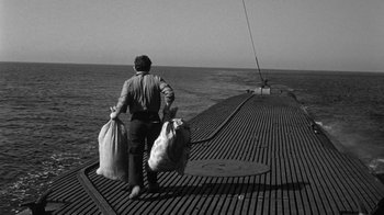 Movie still from “Run Silent Run Deep” (1958), directed by Robert Wise – A man on a boat with two bags of garbage; Wide shot, High angle