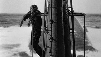 Movie still from “Run Silent Run Deep” (1958), directed by Robert Wise – A black and white photo of a man climbing a metal structure; Wide shot, Low angle