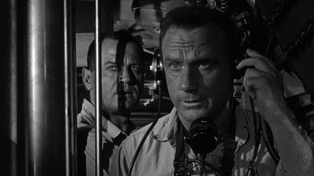 Movie still from “Run Silent Run Deep” (1958), directed by Robert Wise – Two men are standing next to each other in a train; Close Up shot, Low angle