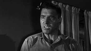 Movie still from “Run Silent Run Deep” (1958), directed by Robert Wise – A black and white photo of a man with a strange look on his face; Close Up shot, Low angle