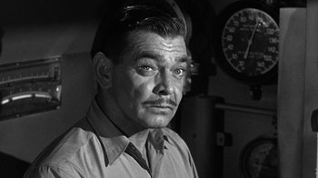 Movie still from “Run Silent Run Deep” (1958), directed by Robert Wise – An older man in a shirt and tie in front of a clock; Close Up shot, High angle
