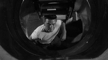 Movie still from “Run Silent Run Deep” (1958), directed by Robert Wise – A black and white photo of a man looking up at the camera; Medium shot, High angle