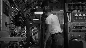 Movie still from “Run Silent Run Deep” (1958), directed by Robert Wise – A man standing in a room looking in a mirror; Medium shot, High angle