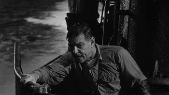 Movie still from “Run Silent Run Deep” (1958), directed by Robert Wise – A man sitting on a boat in the water; Close Up shot, Over the shoulder angle
