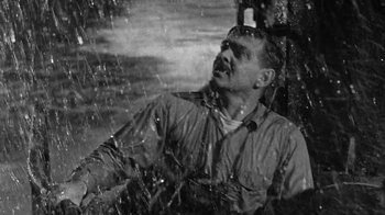 Movie still from “Run Silent Run Deep” (1958), directed by Robert Wise – A black - and - white photo of a man looking up at the sky; Medium shot, High angle