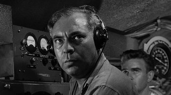 Movie still from “Run Silent Run Deep” (1958), directed by Robert Wise – An older man wearing headphones in front of an old radio set; Close Up shot, Low angle