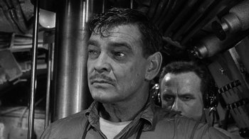 Movie still from “Run Silent Run Deep” (1958), directed by Robert Wise – A black and white photo of a man with a mustache; Close Up shot, Over the shoulder angle