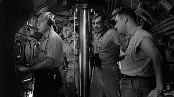 Movie still from “Run Silent Run Deep” (1958), directed by Robert Wise – A black and white photo of a group of men standing next to each other; Medium shot, High angle