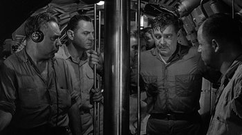 Movie still from “Run Silent Run Deep” (1958), directed by Robert Wise – A black and white photo of a group of men on a subway train; Medium shot, High angle