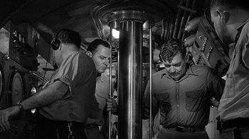 Movie still from “Run Silent Run Deep” (1958), directed by Robert Wise – A black and white photo of a group of men standing in a subway train; Medium shot, High angle