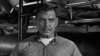 Movie still from “Run Silent Run Deep” (1958), directed by Robert Wise – An older man in a gray shirt is looking at the camera; Close Up shot, Low angle
