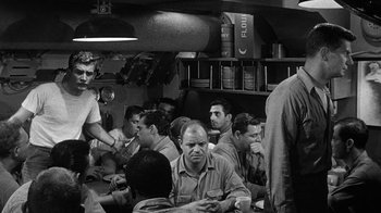 Movie still from “Run Silent Run Deep” (1958), directed by Robert Wise – A black and white photo of a group of men sitting in a room; Medium shot, Over the shoulder angle