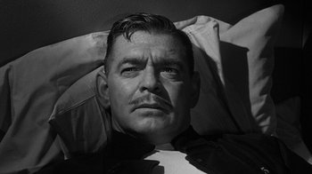 Movie still from “Run Silent Run Deep” (1958), directed by Robert Wise – A black and white photo of a man with a mustache; Close Up shot, High angle