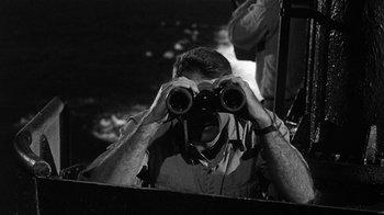 Movie still from “Run Silent Run Deep” (1958), directed by Robert Wise – A man looking through a pair of binoculars; Medium shot, High angle