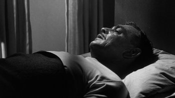Movie still from “Run Silent Run Deep” (1958), directed by Robert Wise – A black and white photo of a man laying on a bed; Close Up shot, High angle