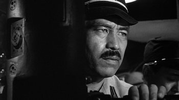 Movie still from “Run Silent Run Deep” (1958), directed by Robert Wise – Black and white photograph of a man in a uniform; Close Up shot, Low angle