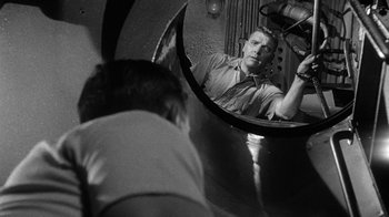 Movie still from “Run Silent Run Deep” (1958), directed by Robert Wise – A man looking into a mirror in front of a mirror; Medium shot, High angle