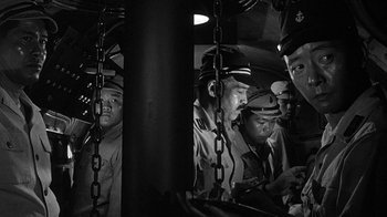 Movie still from “Run Silent Run Deep” (1958), directed by Robert Wise – A black and white photo of a group of men in uniform; Medium shot, High angle