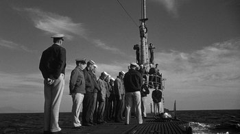 Movie still from “Run Silent Run Deep” (1958), directed by Robert Wise – A black and white photo of a group of men standing on a pier; Wide shot, High angle