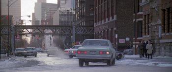 Movie still from “Running Scared” (1986), directed by Peter Hyams – Cars driving down a street in the snow; Wide shot, Over the shoulder angle
