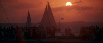 Movie still from “Running Scared” (1986), directed by Peter Hyams – A group of people standing next to a body of water; Extreme Wide shot, Low angle