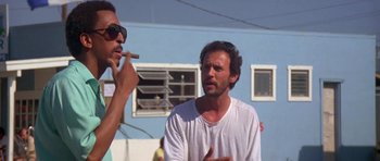 Movie still from “Running Scared” (1986), directed by Peter Hyams – A man talking to another man while holding a cigar; Medium shot, Low angle