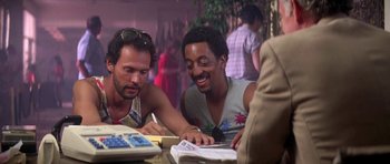 Movie still from “Running Scared” (1986), directed by Peter Hyams – A couple of men sitting next to each other at a table; Close Up shot, Low angle