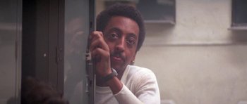 Movie still from “Running Scared” (1986), directed by Peter Hyams – A man leaning against a metal door with his hand on the wall; Close Up shot, Low angle
