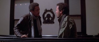 Two men talking to each other in front of a mirror