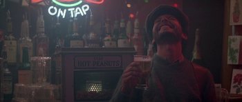 Movie still from “Running Scared” (1986), directed by Peter Hyams – A man holding a glass of beer in a bar; Close Up shot, Low angle