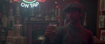 Movie still from “Running Scared” (1986), directed by Peter Hyams – A man holding a glass of beer in front of a bar; Close Up shot, Low angle