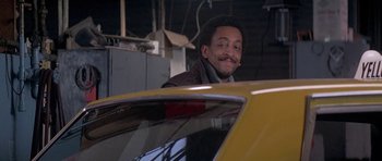 Movie still from “Running Scared” (1986), directed by Peter Hyams – A man with a mustache standing next to a yellow car; Close Up shot, Low angle