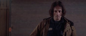Movie still from “Running Scared” (1986), directed by Peter Hyams – A person wearing a brown jacket; Close Up shot, Low angle