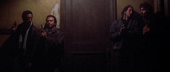 Movie still from “Running Scared” (1986), directed by Peter Hyams – Two men standing in front of a door; Medium shot, Low angle