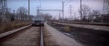 Movie still from “Running Scared” (1986), directed by Peter Hyams – A car driving down a road next to power lines; Extreme Wide shot, Low angle