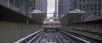 Movie still from “Running Scared” (1986), directed by Peter Hyams – A yellow car driving down a train track in a train station; Extreme Wide shot, High angle