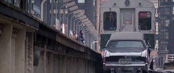 Movie still from “Running Scared” (1986), directed by Peter Hyams – Two people standing on a bridge near a train; Wide shot, Over the shoulder angle