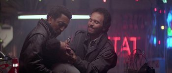 Movie still from “Running Scared” (1986), directed by Peter Hyams – Two men are holding a cell phone in their hands; Close Up shot, Low angle