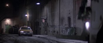Movie still from “Running Scared” (1986), directed by Peter Hyams – A car parked on the side of the road in the dark; Extreme Wide shot, High angle