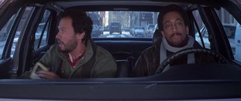 Movie still from “Running Scared” (1986), directed by Peter Hyams – Two men in the back seat of a car; Medium shot, High angle