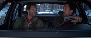 Movie still from “Running Scared” (1986), directed by Peter Hyams – Two men sitting in the back seat of a car; Medium shot, High angle