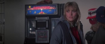 Movie still from “Running Scared” (1986), directed by Peter Hyams – A woman standing in front of an arcade machine; Medium shot, Over the shoulder angle
