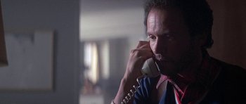 Movie still from “Running Scared” (1986), directed by Peter Hyams – A man talking on a phone while wearing a blue shirt; Close Up shot, Low angle