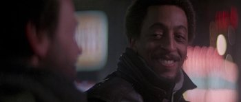 Movie still from “Running Scared” (1986), directed by Peter Hyams – A person smiling; Close Up shot, Over the shoulder angle