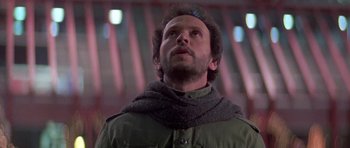 Movie still from “Running Scared” (1986), directed by Peter Hyams – A man wearing a green jacket and a gray scarf; Close Up shot, Low angle