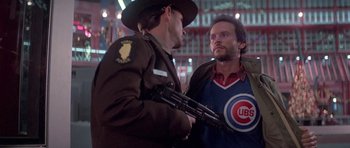 Movie still from “Running Scared” (1986), directed by Peter Hyams – Two men are standing next to each other; Medium shot, Over the shoulder angle