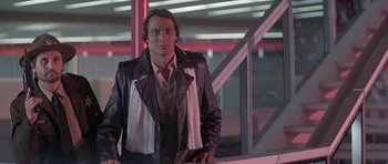 Movie still from “Running Scared” (1986), directed by Peter Hyams – A man wearing a leather jacket and a white scarf; Medium shot, Low angle