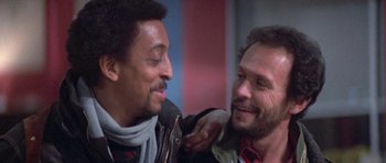 Movie still from “Running Scared” (1986), directed by Peter Hyams – A couple of men standing next to each other; Close Up shot, Low angle